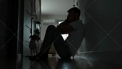 Depressed man sitting on floor in dark room