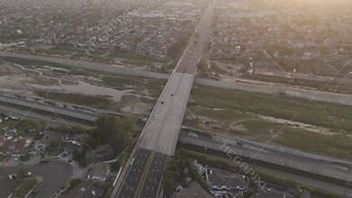 Aerial footage of vehicles driving on Adams Ave crossing Santa Ana river at sunset, California, USA