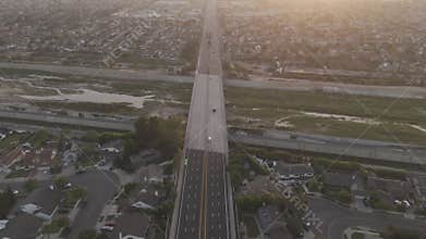 Aerial footage of vehicles driving on Adams Ave crossing Santa Ana river at sunset, California, USA