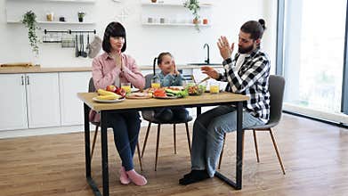 Family prays together before enjoying breakfast meal at home