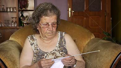 Old retired woman knitting in home