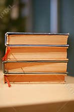 Stacked vintage books with colored spines on a wooden table