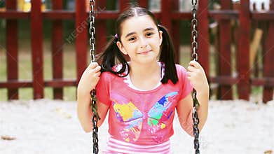 Little girl on swing smiling at camera