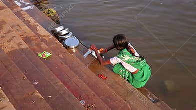 HAMPI, INDIA - APRIL 2013: Local woman washing dishes in river