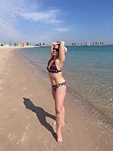 A 50-year-old woman in a bikini sunbathes by the sea on a beach