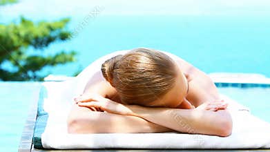 Smiling woman on spa bed next to swimming pool
