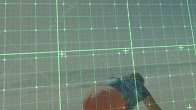 Senior woman crouching shoreline interacting with green grid overlay over ocean in technology