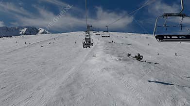 Aerial view over snowy mountain winter forest with chair lift at ski resort.