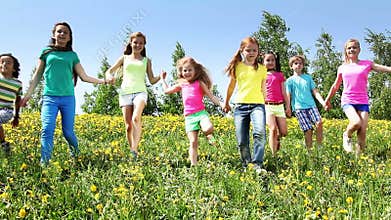 Large group of kids run in dandelion field