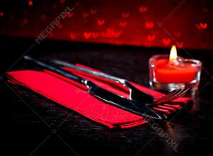 Valentine day table setting with knife, fork, red burning heart shaped candle