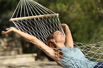 Happy woman relaxing on a hammock on holidays and raising arms