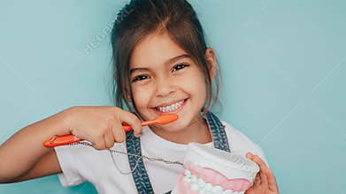 smiling mixed raced girl brushing teeth at blue background