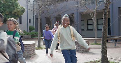 African American children exiting shaded walkway, running toward open courtyard with backpacks