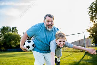 Dad and son having fun while practicing football outdoors.