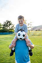 Dad and son having fun while practicing football outdoors.
