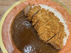 Crispy pork cutlet with brown curry sauce and white rice on plate, savory comfort food with golden crust