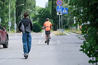 Cyclist And Electric Scooter Rider Sharing Urban Road