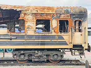 Train car in abandoned railway yard, rusted condition, deteriorated metal surface, peeling paint, muted earthy colors, natural