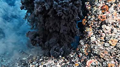 Underwater hydrothermal vent releases black smoke above mineral chimney on deep seabed, revealing rugged seafloor