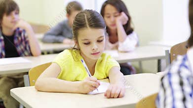 Group of school kids writing test in classroom