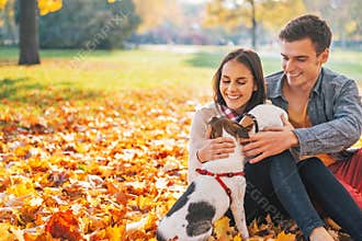 Portrait of happy young couple sitting outdoors in autumn park