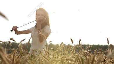 Girl violinist playing the violin in wheat field.