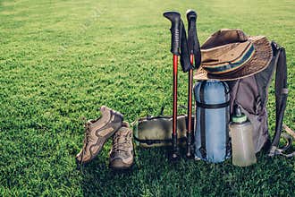 trekking poles, boots, backpack, sleeping bag and other equipment backpacker, on the green grass with beautiful