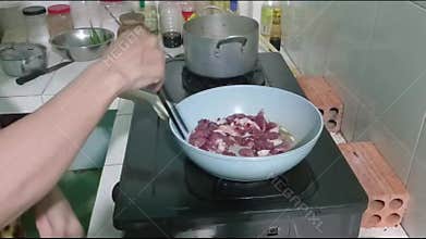 Close Up of Woman Cooking Marinated Meat in Hot Pan With Chopsticks on Gas Stove