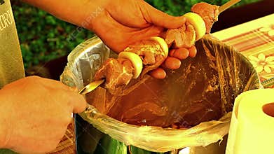 Marinated raw meat, chev-pofar with black gloves prepares, threading on a skewer, close-up.