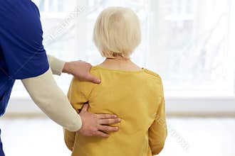 Osteopath examines a senior woman spinal in a medical center. Posture correction and back pain treatment