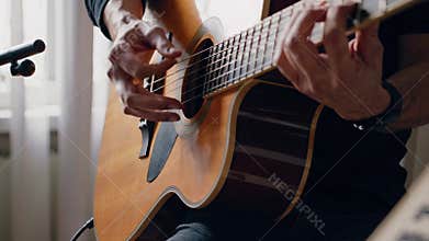 Musician plays acoustic guitar at home. Passionate performance creates soothing atmosphere. Music notes visible, enhancing