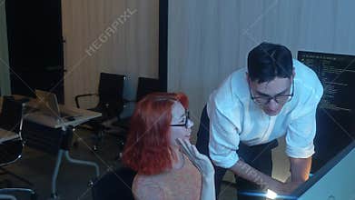 Programmers working at night analyzing code on monitors in a modern office