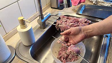 Man Threading Marinated Lamb Meat onto Skewers for Barbecue.
