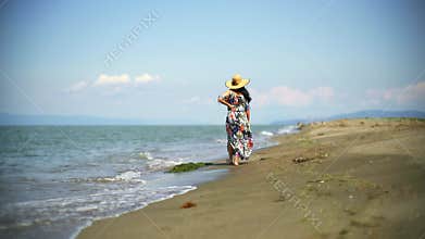 Barefoot woman walks along sandy beach with colorful skirt, sea waves calm summer atmosphere, carries, carries slippers, female