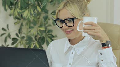 Girl smiling, drinking coffee and looking at
