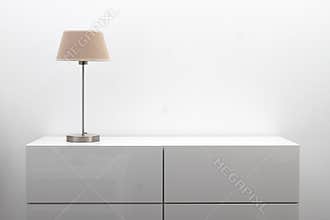 White commode with table lamp in bright minimalism interior