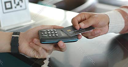 Two men, clerk steadying reader while customer presenting, adjusting chip card at counter paying
