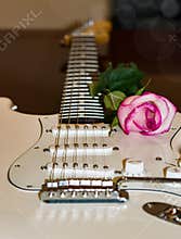 White guitar with a pink rose on the side of soundboard