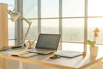 Side view picture of studio workplace with blank notebook, laptop. Comfortable work table, home office.