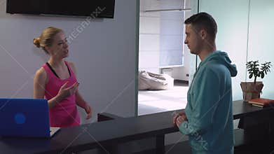 Manager in yoga center has conversation with customer.