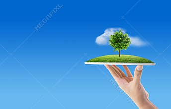 Hand holding tablet computer with grass and tree of nature background with environment concept.