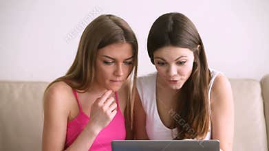 Two excited pretty girls using laptop, shopping online on sale