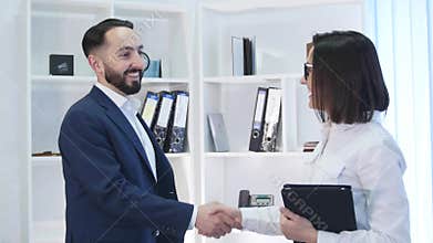 Business handshake - two businesspeople shaking hands to conclude deal or agreement