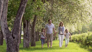 Happy family walking in summer Park near the blossoming Apple trees. father, mother and two daughters spend time
