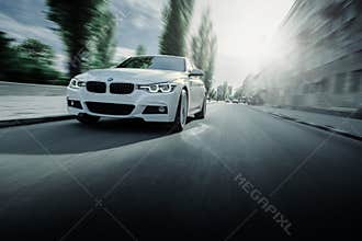 White BMW 3 Series F30 car is driving on asphalt road at summer daytime