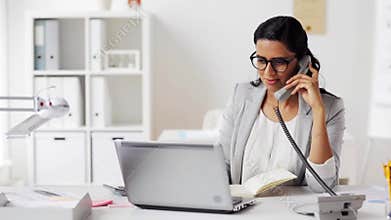 Businesswoman with pad calling on phone at office