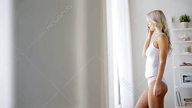 Woman in underwear calling on smartphone at home