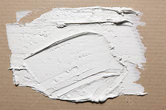 Rough texture of smeared white stucco on cardboard