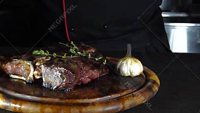 Fried steak on the grill lies on a wooden board with vegetables