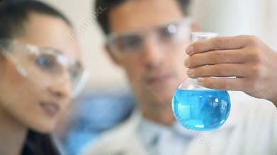 Chemists working together and looking at a test tube in a clinical laboratory.